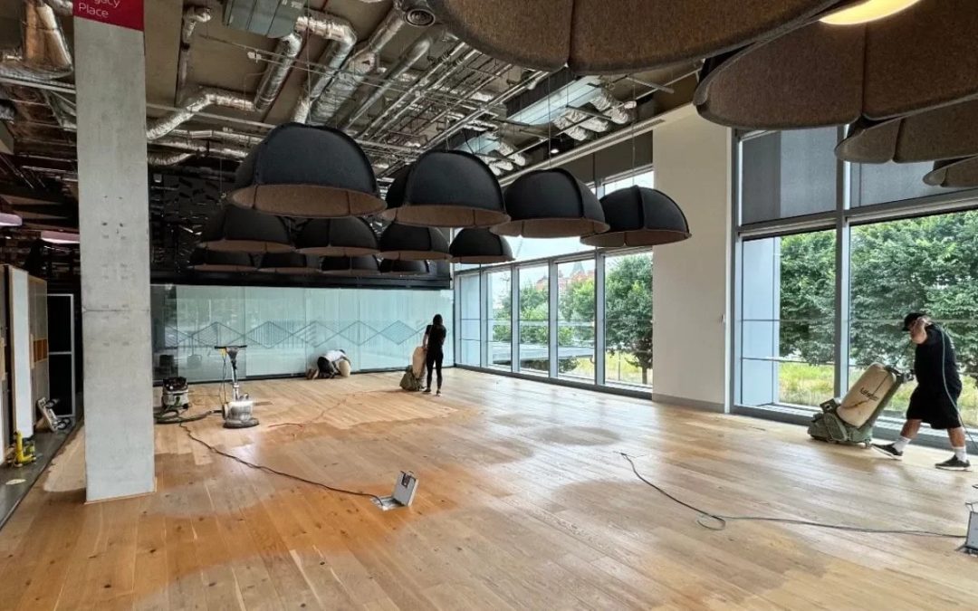 Commercial Floor Sanding in Upminster: technicians sanding engineered oak plank flooring in a modern office using dust-controlled machines.
