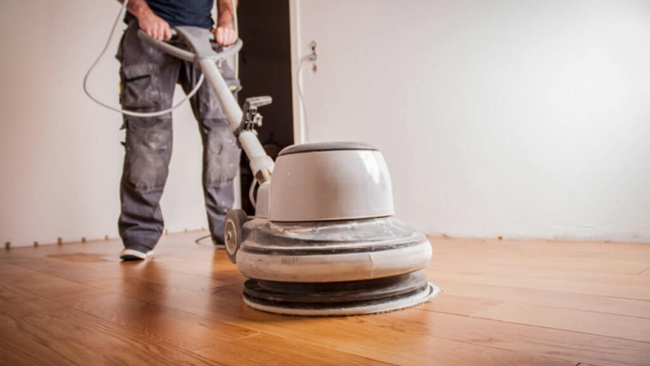 Commercial Floor Sanding in Upminster: technician using a rotary buffer to screen engineered oak plank flooring for a smooth, even finish.