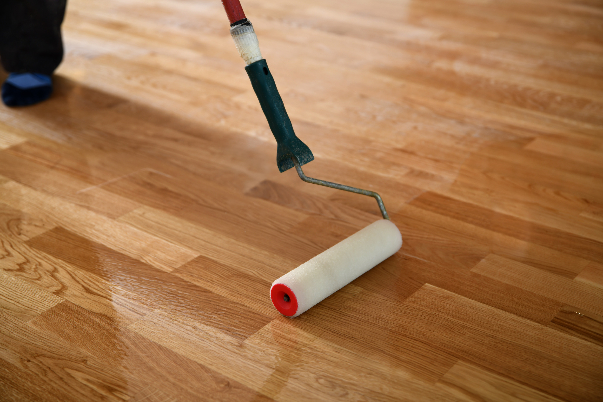 Hardwood Floor Refinishing in Upminster with a roller applying clear finish to an engineered oak hardwood floor for a smooth, like-new surface